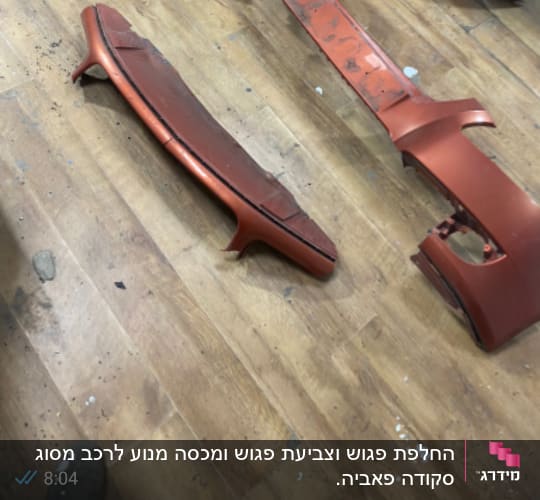 חלקי פגוש רכב מפורקים על רצפת עץ